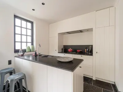 a kitchen with white cabinets and a black counter top at Scenic villa in Borgloon with garden in Borgloon