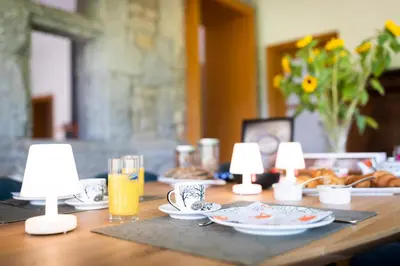 a wooden table with lamps and plates and drinks on it at Côté cour, côté source chambre d'hôtes in Chaudfontaine