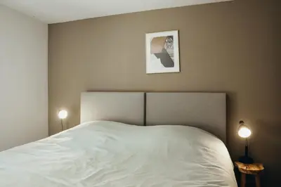 a bedroom with a large white bed with two lamps at L'Orée du Bois by WelcHome in Verviers
