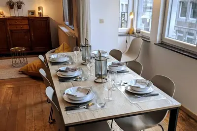a wooden table with chairs and plates and wine glasses at Liège City by WelcHome in Liège