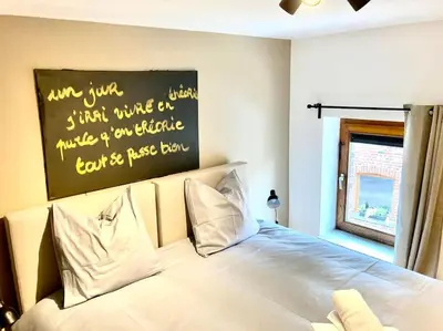a bedroom with a white bed with a sign above it at Le Val du Cossart by WelcHome in Verviers