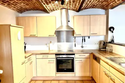 a kitchen with wooden cabinets and a stove top oven at Le Val du Cossart by WelcHome in Verviers