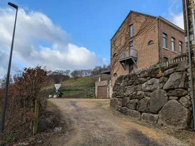 an old brick building next to a stone wall at Le Voisin du Pré by WelcHome in Verviers
