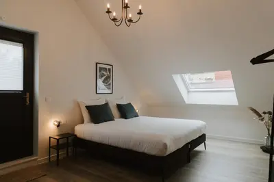 a bedroom with a bed and a chandelier at Bij de secretaris in Kanne