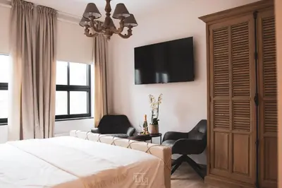 a bedroom with a bed and two chairs and a tv at La Forteresse in Borgloon