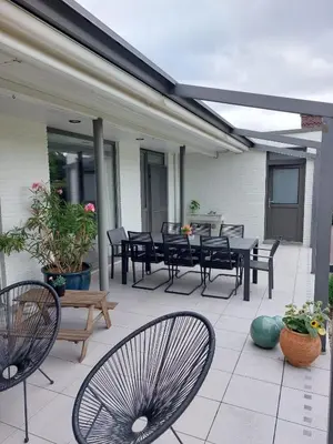 a patio with black tables and chairs on a house at Vakantiewoning De Papendaler in Zutendaal