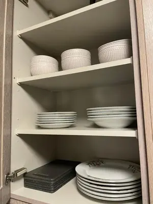 a cabinet filled with white plates and bowls on shelves at Chalet Sint-Hubertus Du Bois in Zutendaal