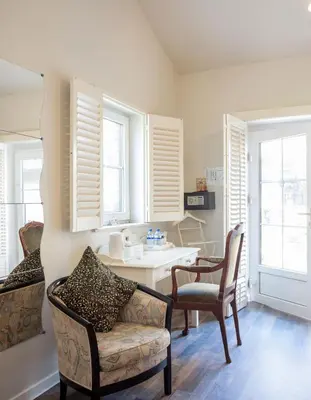 a living room with a desk and chairs and windows at B&B AntiQua & Qook in Tongeren