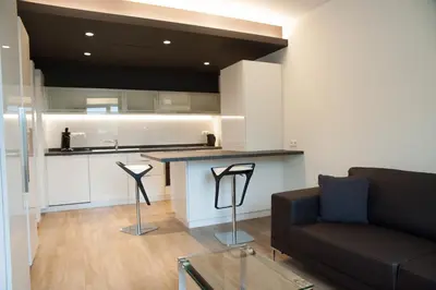 a living room with a couch and a kitchen at Appart'hotel Urban Lodge in Chaudfontaine