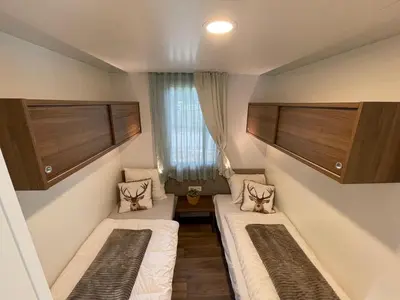 a small room with two beds and a window at Chalet Het Edelhert in Zutendaal