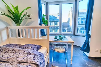 a bedroom with a bed and a table and windows at Studio Hyper centre - Cathédrale in Liège