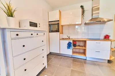 a kitchen with white cabinets and a tile floor at Studio Hyper centre - Cathédrale in Liège