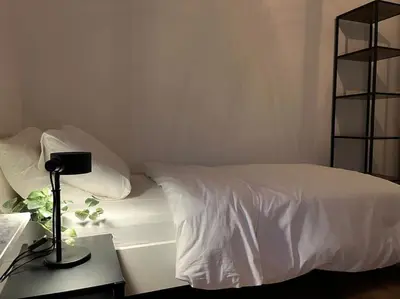 a bed with white sheets and a lamp on a table at Boldermountain Guesthouse in Heusden - Zolder