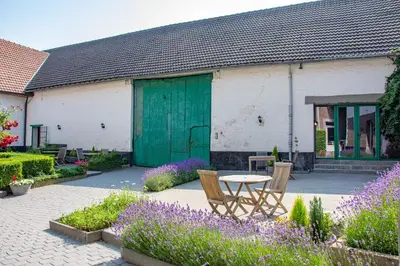 a table and chairs in a garden with purple flowers at B&B De Oude Winning in Riemst