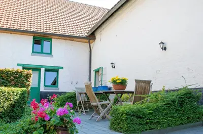 a patio with a table and chairs and flowers at B&B De Oude Winning in Riemst