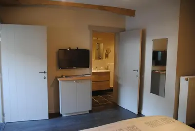 a bedroom with a television and a bathroom with a sink at B&B De Oude Winning in Riemst