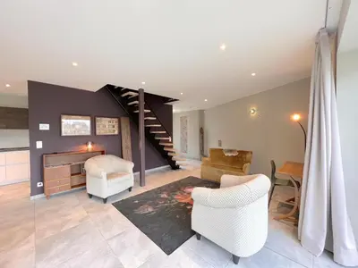 a living room with a staircase and white chairs at Achter de Hegge in Riemst