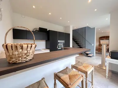 a kitchen with black cabinets and a counter with chairs at Achter de Hegge in Riemst