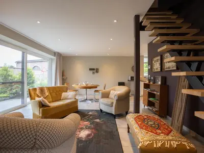 a living room with couches and a spiral staircase at t Bakhuys in Riemst
