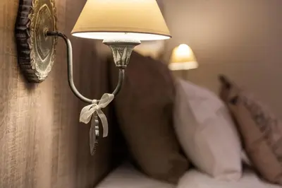 a lamp on a wall next to a bed at Hôtel de la Tour in Melen