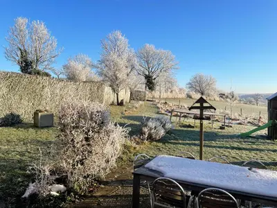 a table and chairs in a field with trees at À la Belle Vue in Limbourg