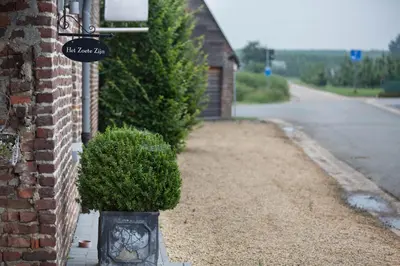 a sign on the side of a house with a bush at Luxe hoeve voor groepen tot 26 personen in Borgloon in Borgloon