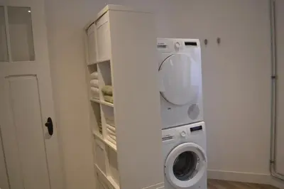 a washer and dryer in a white laundry room at De zwarte deur in Genk