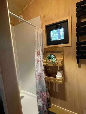 a bathroom with a tv and a shower curtain at Pipowagen de Pauw in de bossen van Belgisch Limburg nabij Maastricht in Lanaken