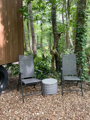 two chairs and a table in front of a statue at Pipowagen de Pauw in de bossen van Belgisch Limburg nabij Maastricht in Lanaken