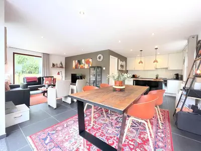 a kitchen and living room with a wooden table and chairs at De Lelie in Rekem