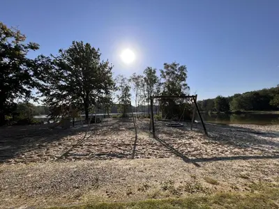 an empty swing set on the shore of a lake at De Lelie in Rekem