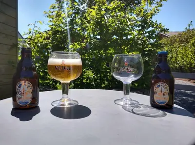 two bottles and two glasses of beer on a table at Côté jardin in Dison