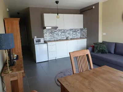 a kitchen and a living room with a table and a couch at Het Zonnetje -Vakantiewoning en Bed and Breakfast in Dilsen-Stokkem