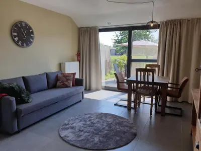 a living room with a couch and a table and a clock at Het Zonnetje -Vakantiewoning en Bed and Breakfast in Dilsen-Stokkem