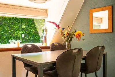 a dining room table with chairs and a vase of flowers at Boshuisje Rekem - Flora in Lanaken