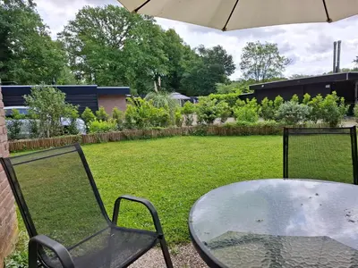 a table and chair with an umbrella in a yard at Zonnige vrijstaande bungalow in prachtige omgeving! in Rekem