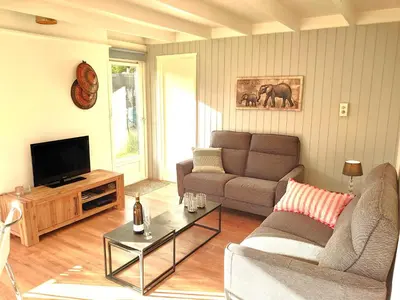 a living room with a couch and a tv at Zonnige vrijstaande bungalow in prachtige omgeving! in Rekem