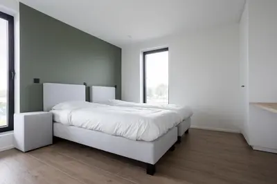 a bedroom with a white bed and a large window at NIEUW - De Grenspaal WEST 6P 5 min Maastricht - Sauna - Laadpaal in Riemst