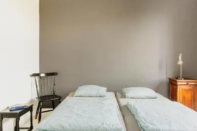 two beds in a room with a chair and a table at Beautiful mansion with swimming pool and jacuzzi in Bilzen