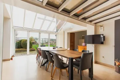 a dining room with a table and chairs and a large window at Beautiful mansion with swimming pool and jacuzzi in Bilzen