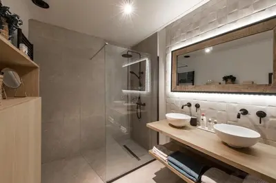 a bathroom with a shower and two sinks and a mirror at Vakantiewoning 'De Teut' in Zonhoven