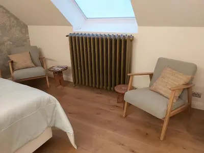a bedroom with a bed and a radiator and two chairs at B&B Asmara in Maasmechelen