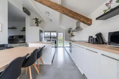 a kitchen with white countertops and black chairs at Le Gîte du Moulin - Modernity & Elegance - jacuzzi in Oupeye