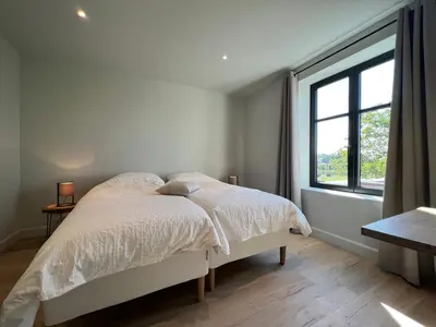 a white bedroom with a bed and a window at Huis Hygge in Peer