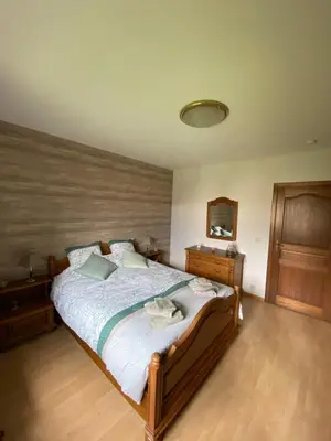 a bedroom with a large bed with a wooden floor at Le Logis du Plateau in Herve