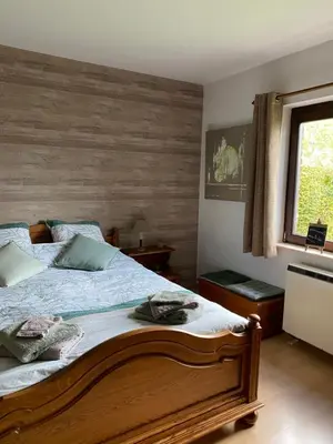a bedroom with a bed with a wooden wall at Le Logis du Plateau in Herve