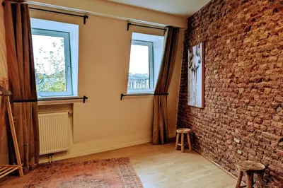 a room with a brick wall and two windows at La Tour by WelcHome in Verviers