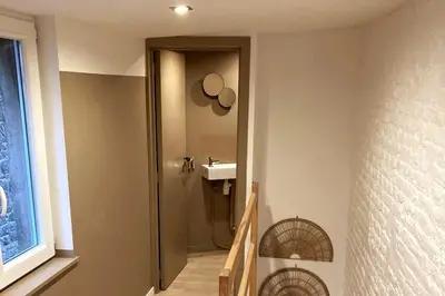 a hallway with a bathroom with a sink and a mirror at La Tour by WelcHome in Verviers