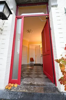 an open red door in a white building with fruit on the floor at Le Chateau Blanc in Verviers
