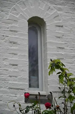 a window in a white brick building with two roses at Le Chateau Blanc in Verviers